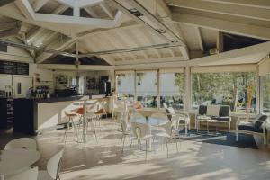 un restaurante con sillas blancas, mesas y ventanas en Amalurra Ecohotel & Retreat Center, en Artzentales