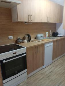 a kitchen with wooden cabinets and a stove top oven at Apartament Osiedle Bajkowe in Ostrów Wielkopolski
