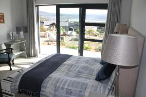 a bedroom with a bed and a large window at Heron's View - lagoon views and solar power @Lake Brenton, Knysna in Knysna