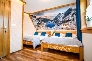 two beds in a room with a mountain mural at Domki u Górala in Zakopane