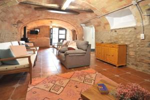 a living room with couches and a stone wall at Casa del silencio Can Baldoyra in Espinavesa