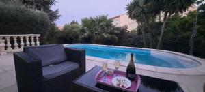 een fles wijn op een tafel naast een zwembad bij Maison proche de Hyeres avec piscine privée, terrasse et jardin in La Farlède