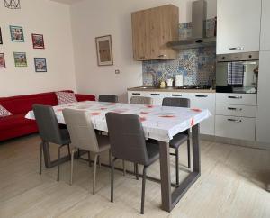 eine Küche mit einem Tisch und Stühlen sowie einer roten Couch in der Unterkunft La casa sotto il Fortino in SantʼAntìoco