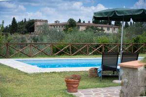 a swimming pool with two chairs and an umbrella at Villa Sunset in Greve in Chianti