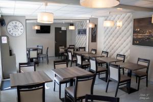 a restaurant with wooden tables and chairs and a clock at Hotel de la Cathedrale in Beauvais