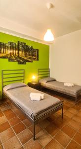 two beds in a room with a green wall at La Pinetina in Ancona