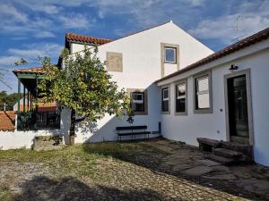 una casa blanca con un banco delante en Casa Trebaruna - refúgio numa aldeia do interior en Proença-a-Velha