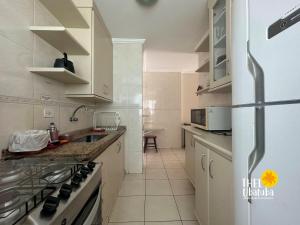 eine weiße Küche mit einem Kühlschrank und einer Spüle in der Unterkunft Conforto, 2 vagas garag lazer a poucos passos do mar! Apto 306/B, Ana Luiza - Praia Grande in Ubatuba