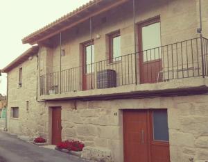 un edificio de piedra con puertas rojas y balcón en Casa MENDEZ - ALLARIZ, en Ourense