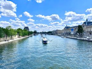 łódź płynąca wzdłuż rzeki w mieście w obiekcie Room in Apartment - Cosy place in the Hear of Paris w Paryżu