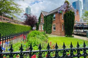 een stenen huis met een zwart hek en bloemen bij Lock Keepers Cottage - Detached House in the city in Manchester