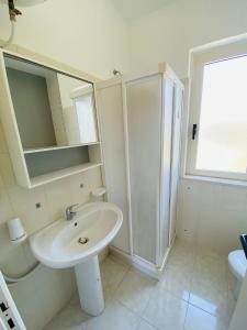 y baño blanco con lavabo y ducha. en Marasusa Apartments Scirocco en Parghelia