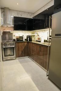 una cocina con armarios de madera y electrodomésticos de acero inoxidable en Luxurious apartment for rent, en Kafr al ‘Ilw