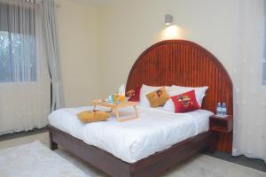 een bed met een houten hoofdeinde met kussens en een tafel erop bij Waves of Love Apartment in Kampala
