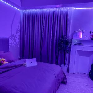 um quarto roxo com uma cama e uma janela em Gold Coast Pantai Indah Kapuk Joy em Jakarta