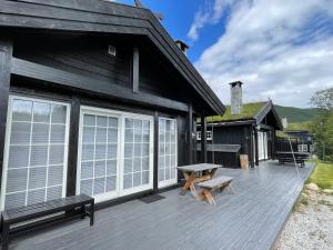 een houten terras met een picknicktafel en een gebouw bij Tuftebo with hiking trails just right outside the door 