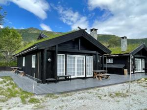 een zwarte hut met een houten terras en banken bij Tuftebo with hiking trails just right outside the door 