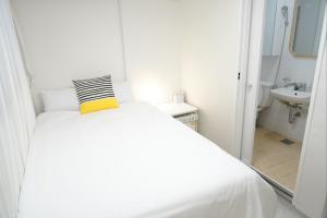 a white bed with a yellow pillow in a bathroom at Coco Stay in Seoul +82 photos
