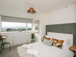 Un dormitorio con una gran cama blanca y una ventana en Dolwyn en Menai Bridge