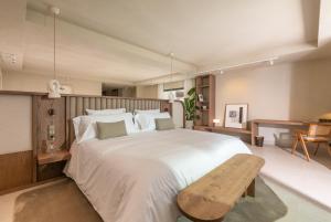 マルベーリャにあるAnfitrión Villas & Suitesのベッドルーム(白い大型ベッド1台、木製ベンチ付)