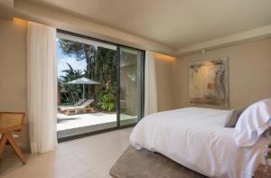 Anfitrión Villas & Suites في مربلة: غرفة نوم بسرير ونافذة زجاجية كبيرة