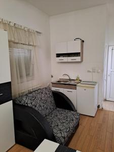 une petite cuisine avec un canapé noir dans une chambre dans l'établissement Guest House Zoran, à Kragujevac