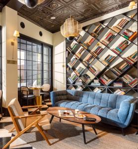a living room with a blue couch and a wall of books at Villa Brown Tel-Aviv, a member of Brown Hotels in Tel Aviv