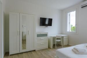 a white bedroom with a desk and a tv on the wall at Yourbanflat White River 2 in Padova
