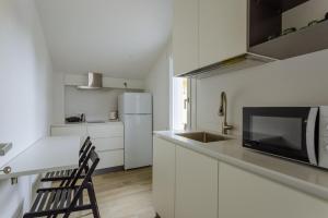 a kitchen with white cabinets and a white refrigerator at Yourbanflat White River 2 in Padova