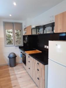 a kitchen with black counter tops and a white refrigerator at LA DOVA MARMOTTE in Brides-les-Bains