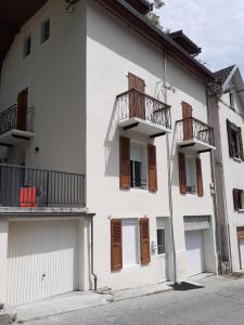 a white building with brown doors and balconies at LA DOVA MARMOTTE in Brides-les-Bains