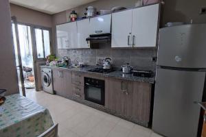 cocina con armarios blancos y nevera blanca en Appartement à Blanca Beach., en Casablanca