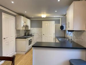 a kitchen with white cabinets and a black counter top at Stunning 4-Bedroom Home in Basingstoke