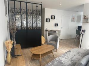 Una sala de estar con una cama, una mesa y un escritorio. en Studio récent, entièrement équipé, proche Chantiers et Airbus, en Saint-Nazaire