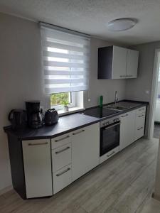 uma cozinha com armários brancos e um balcão preto em Haus Angel-am See em Heldrungen