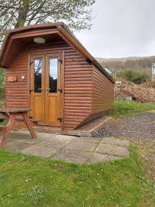 a wooden cabin with a door in the grass at Cruachan Caravan and Camping Farm in Killin