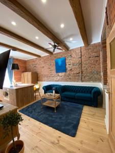 a living room with a blue couch and a brick wall at Apartments PSD - Anny Łajming 1A in Słupsk