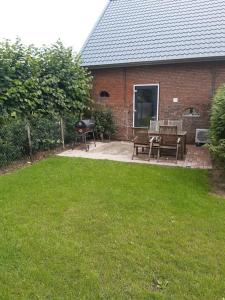 a backyard with a grill and chairs and a house at appartement in authentiek koetshuis met bedstee in Moerstraten