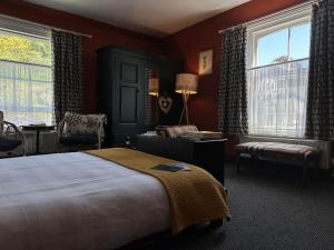 a bedroom with a bed and a chair and windows at One Drake Road, Tavistock, Devon in Tavistock