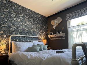 a bedroom with a bed with a floral accent wall at One Drake Road, Tavistock, Devon in Tavistock