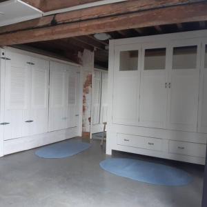 a large room with white cabinets and blue mats at appartement in authentiek koetshuis met bedstee in Moerstraten