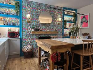 cocina con paredes azules y mesa con espejo en One Drake Road, Tavistock, Devon en Tavistock