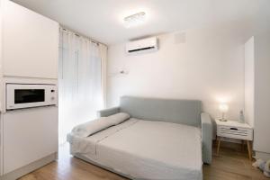 ein weißes Schlafzimmer mit einem Bett und einem Nachttisch in der Unterkunft Estudio Limón y Sal in Chiclana de la Frontera