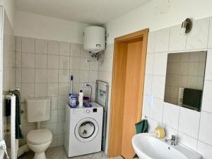 a bathroom with a toilet a sink and a washing machine at Engelhard´s Ferien Apartment 