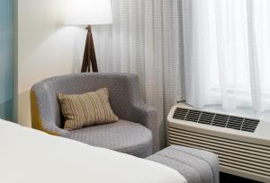 1 dormitorio con silla, cama y ventana en Courtyard by Marriott Hilton Head Island en Hilton Head Island