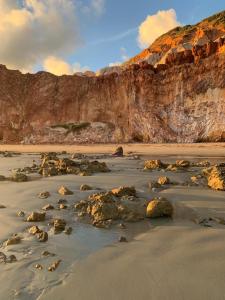 una playa con rocas en la arena y un acantilado en Uma casa para descansar em um cenário paradisíaco., en Icapuí