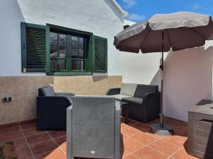 eine Terrasse mit einem Tisch und einem Sonnenschirm in der Unterkunft Casa El Eco del Volcán 2 in Teguise