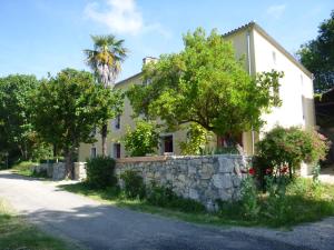 a house with a stone wall next to a street at Les Terrasses De Bessou in Clermont-Dessous