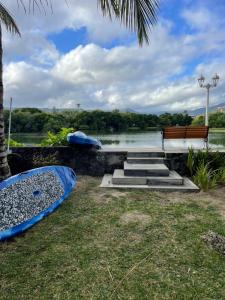 a bench and kayaks on the grass next to a lake at Between 2 waters Villa, free rental car offered. in Tamarin