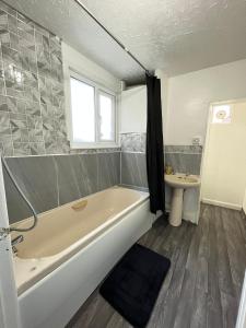 a bathroom with a tub and a sink at Lovely Guest House in Kent